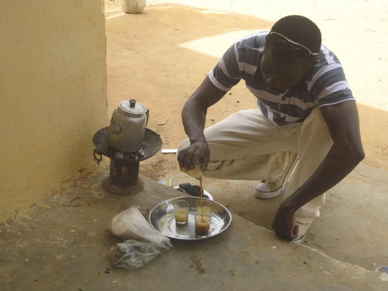 Pape Ba, CREATE! Driver and Field Assistant, makes attaya using a charcoal stove.