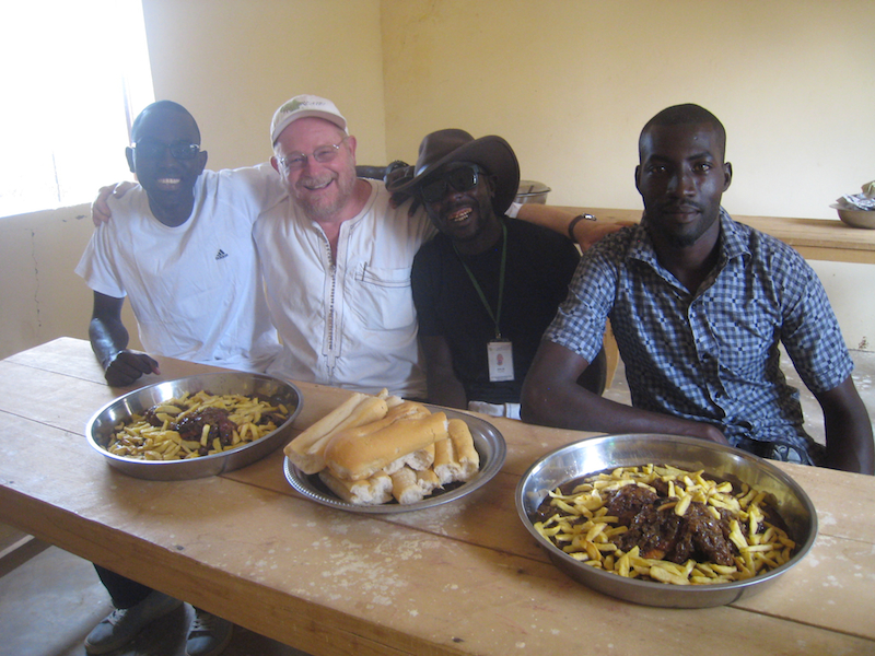 CREATE! staff members Omar Ndiaye Seck, Barry Wheeler, Pape Ba, and Amadou Diouf (left to right) enjoy chicken yassa prepared by cooperative members using their own poultry.