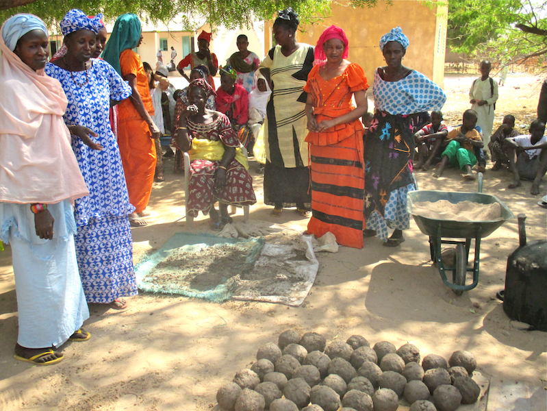 Participants constructed the model improved cookstove using dried grass, sand, clay, and water. After combining the ingredients together, women formed the mixture into balls.