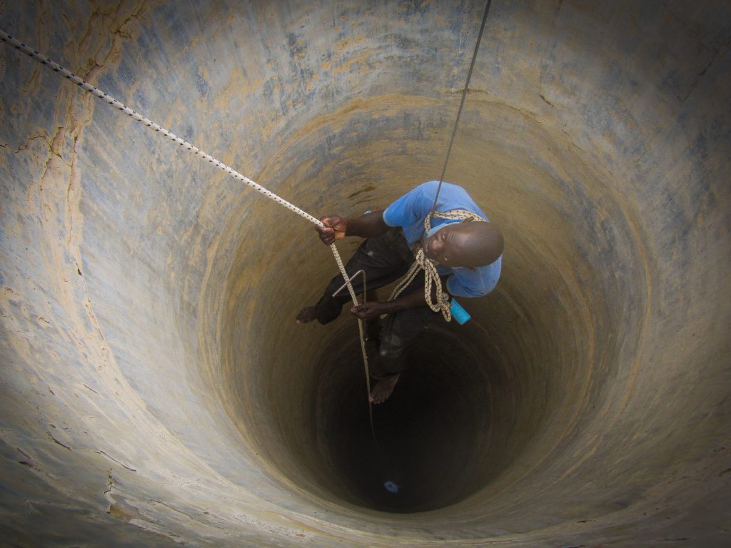 Well rehabilitation: Volunteers are lowered down into the well to clean out the debris